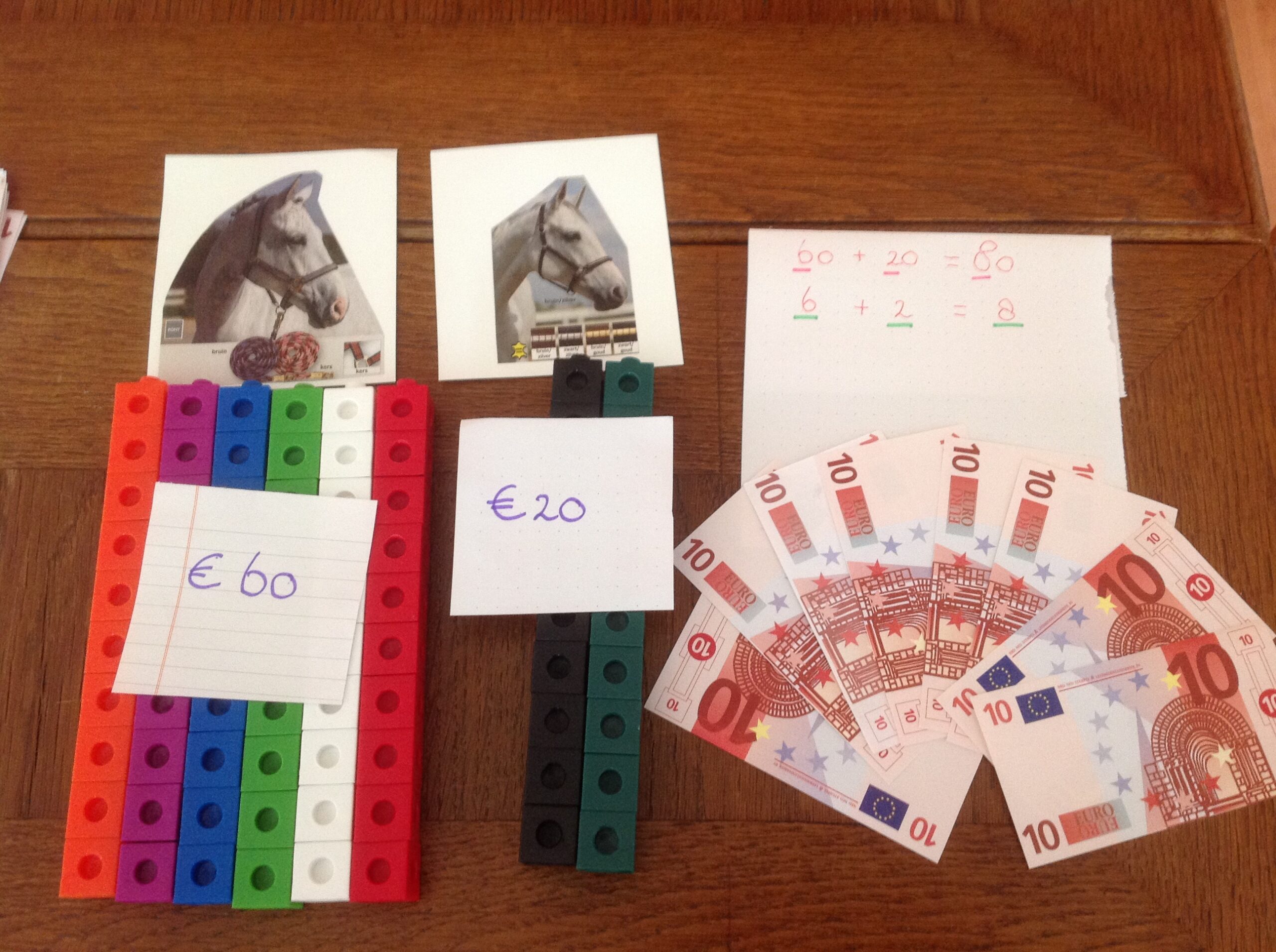 Een rekensom van 60+20 met briefjes van tien en unifix gelegd.